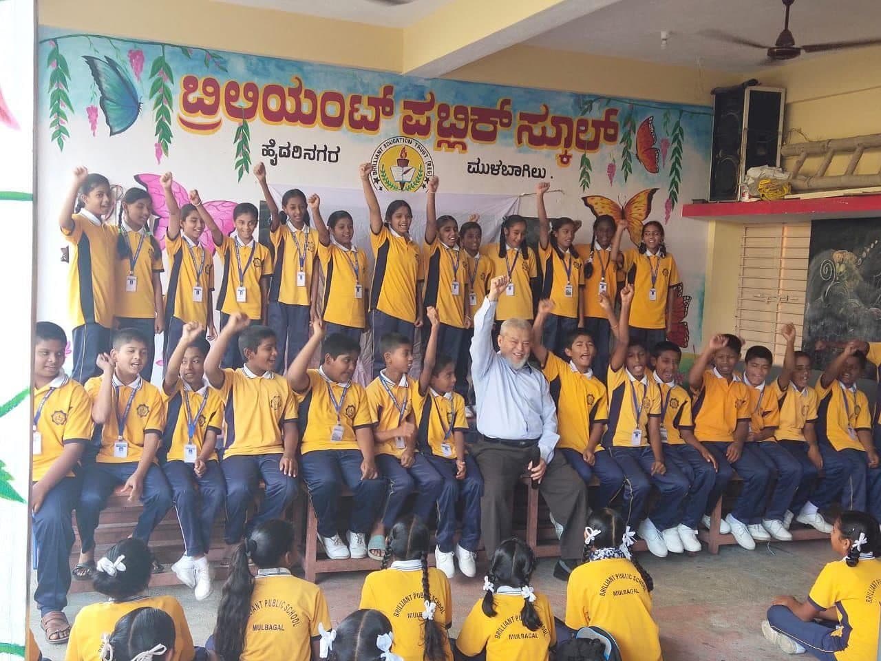 Children at a UZAK mentorship programme in Mulbagal, smiling with their hands raised